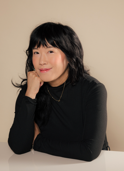 Photo of author Eileen Lee sitting a table smiling at the camera